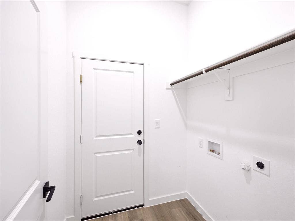 5365 Rabbit Trail, Kemp, TX 75143 Utility area featuring wood-finish flooring, a solid-core paneled door with matte black hardware, built-in shelving with hanging rod, and dedicated washer and dryer hookups
