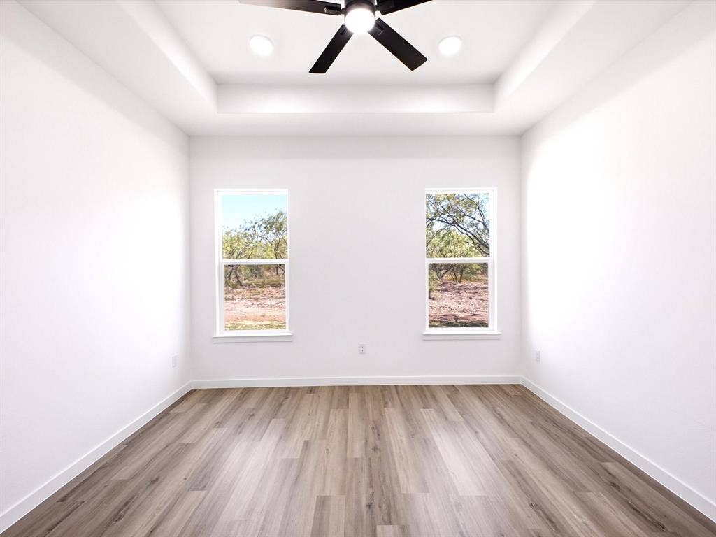 5365 Rabbit Trail, Kemp, TX 75143 Tray ceiling featuring a central ceiling fan and recessed lighting, paired with wood-finish flooring and dual windows