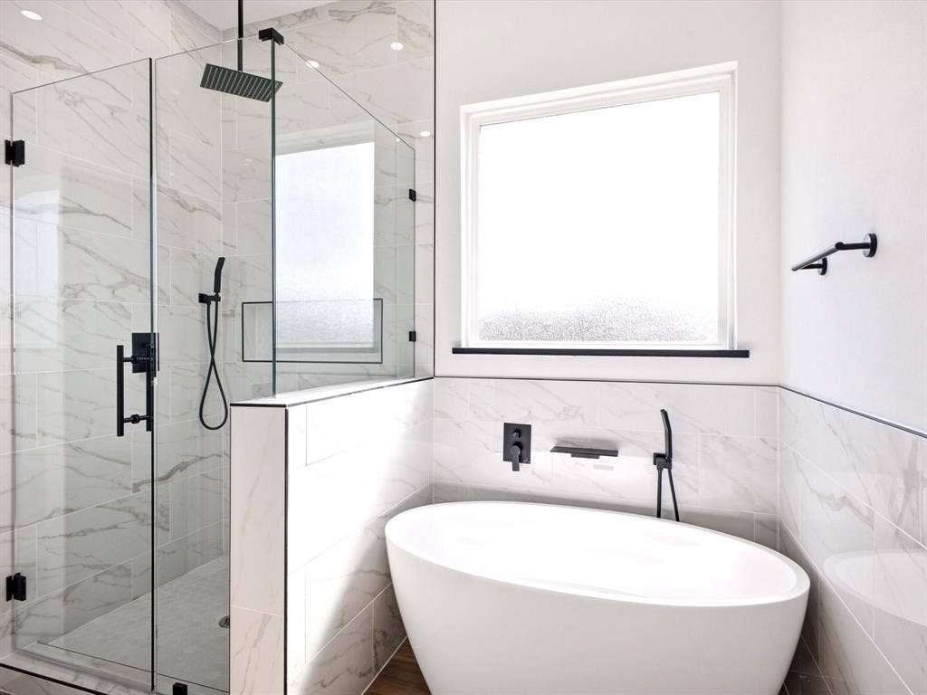 5365 Rabbit Trail, Kemp, TX 75143 Walk-in glass shower featuring matte black hardware, rainfall showerhead, and wall-mounted hand sprayer, paired with a freestanding soaking tub, matte black wall-mounted faucet, and floor-to-ceiling stone-look tile