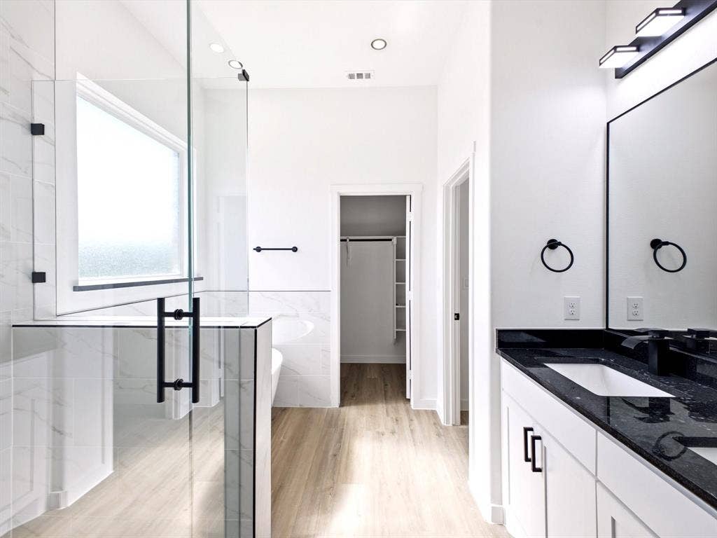 5365 Rabbit Trail, Kemp, TX 75143 Bathroom featuring a frameless glass shower enclosure, stone countertop vanity, matte black fixtures, wood-finish flooring, and built-in closet shelving