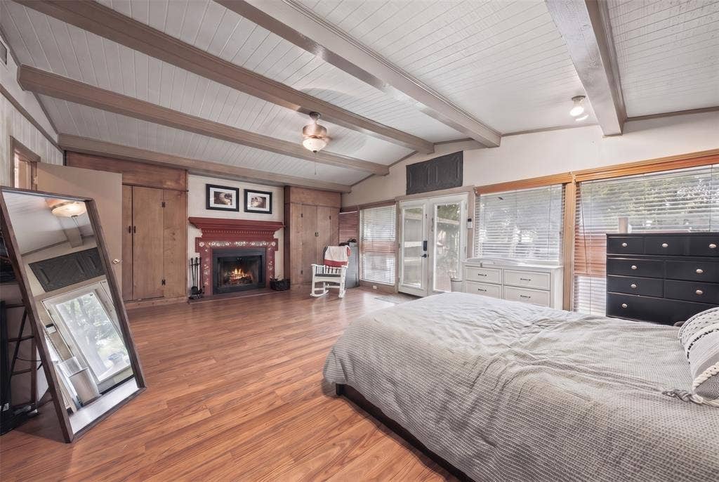406 Summit Street, Farmersville, TX 75442 Vaulted ceiling with exposed wood-finish beams, wood-finish flooring, built-in wooden cabinetry, fireplace with a decorative mantle, and glass-paneled double doors