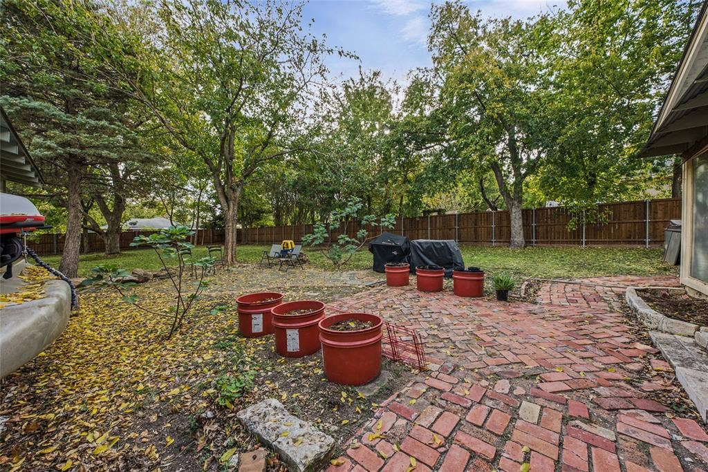406 Summit Street, Farmersville, TX 75442 Expansive backyard featuring a brick paver patio, mature trees, and a wooden perimeter fence