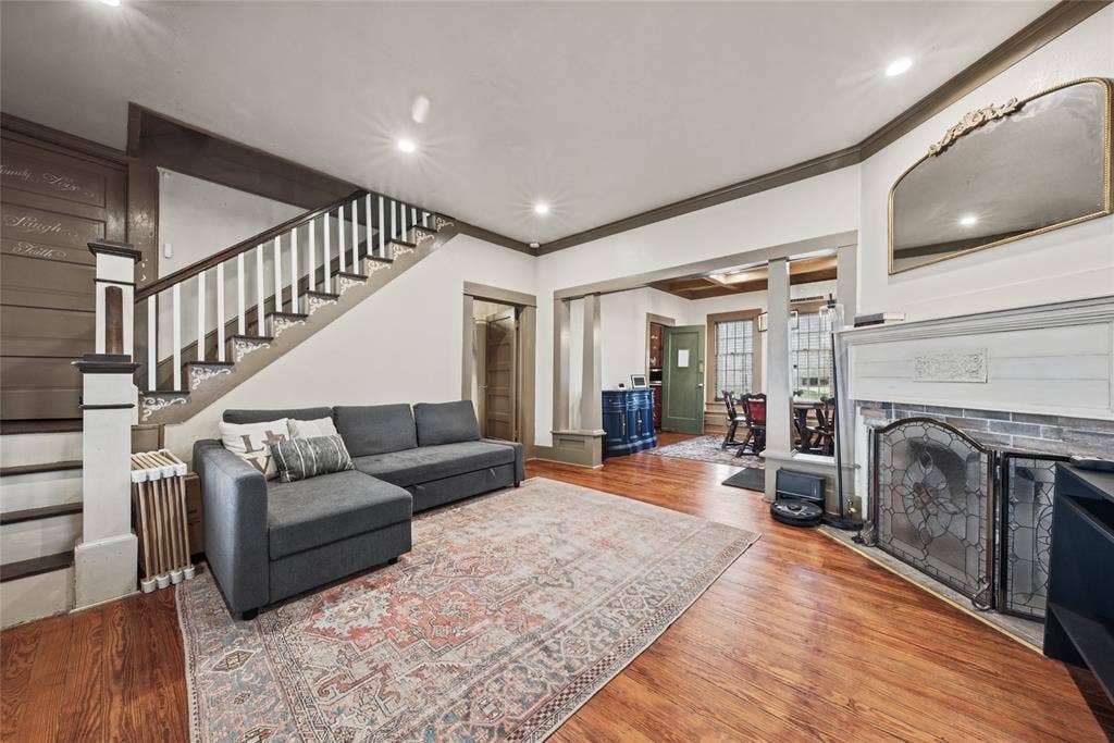 406 Summit Street, Farmersville, TX 75442 Staircase with white balusters and wood-finish handrail, fireplace with brick surround and decorative mantle, recessed lighting, and wood-finish flooring