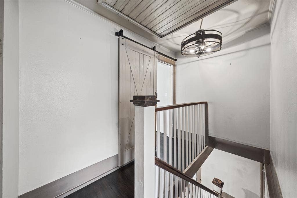 406 Summit Street, Farmersville, TX 75442 Sliding barn-style door, dark-toned flooring, white spindle railing, and a drum-style pendant light fixture