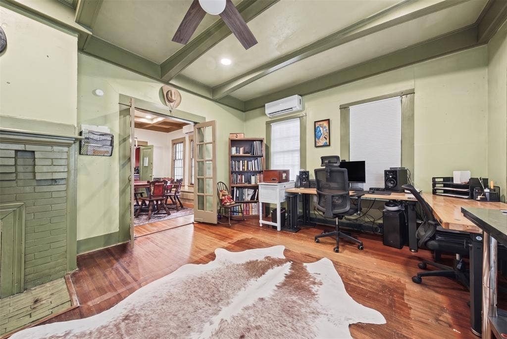 406 Summit Street, Farmersville, TX 75442 Room featuring hardwood flooring, beamed ceiling, painted brick fireplace, and dual-pane windows with trim casing
