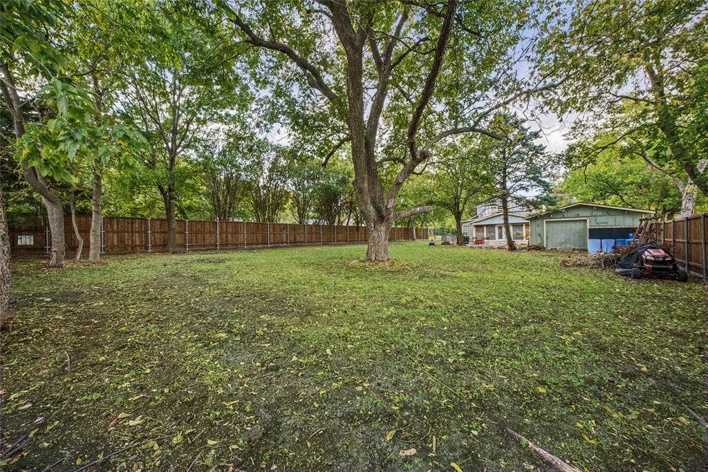 406 Summit Street, Farmersville, TX 75442 Expansive backyard featuring mature shade trees, a tall wood privacy fence, and a detached structure