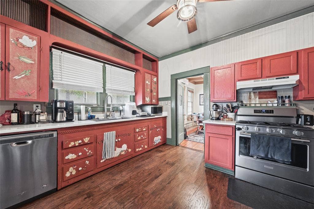406 Summit Street, Farmersville, TX 75442 Kitchen featuring wood-finish flooring, custom cabinetry with integrated shelving, stainless steel dishwasher, gas range with hood, and beadboard wall paneling