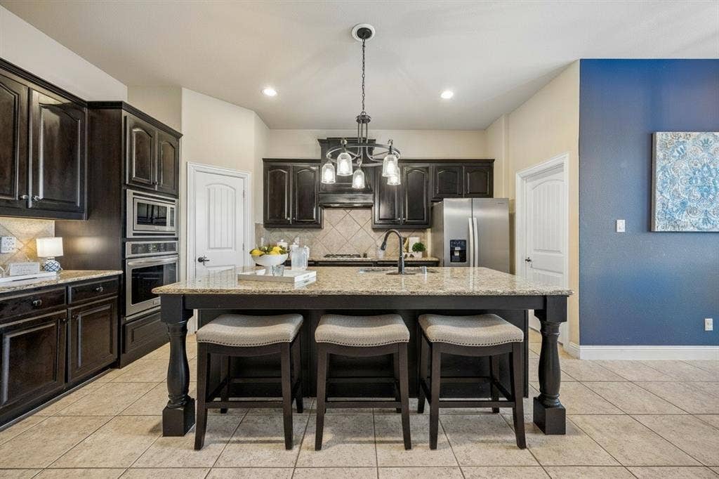 3702 Harlan Drive, Sachse, TX 75048 Kitchen island provides additional prep space and seating while keeping the kitchen connected to the main living areas.