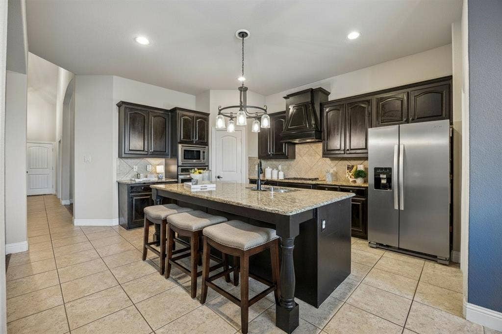 3702 Harlan Drive, Sachse, TX 75048 Open kitchen offers granite countertops, stainless steel appliances, abundant cabinetry, island seating and an upgraded kitchen faucet.