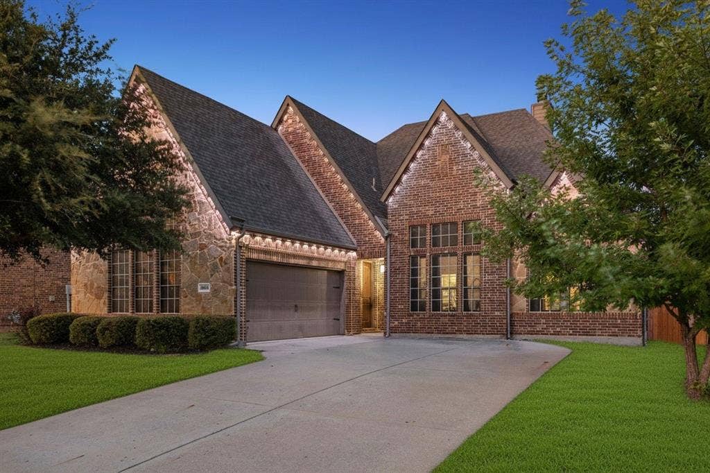 3702 Harlan Drive, Sachse, TX 75048 Twilight curb appeal highlights the home's brick and stone exterior, front-entry garage and permanent Govee outdoor lighting.