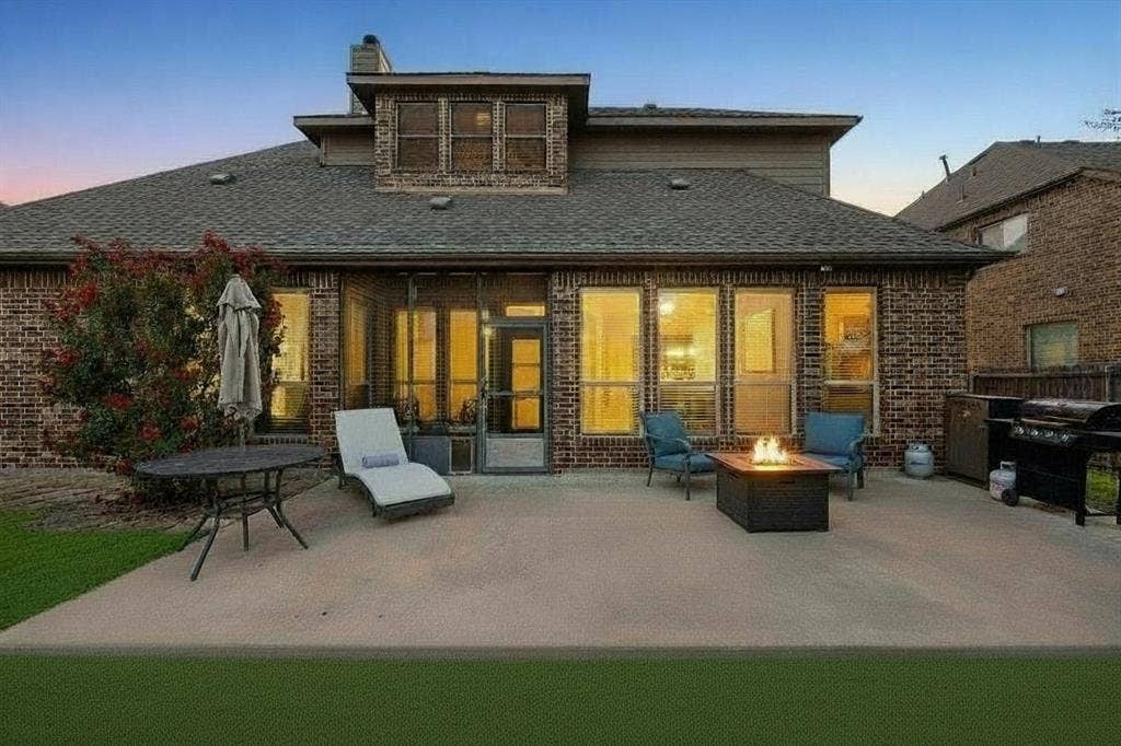 3702 Harlan Drive, Sachse, TX 75048 Evening view of the backyard and covered outdoor living area creates an inviting setting for relaxing or entertaining.