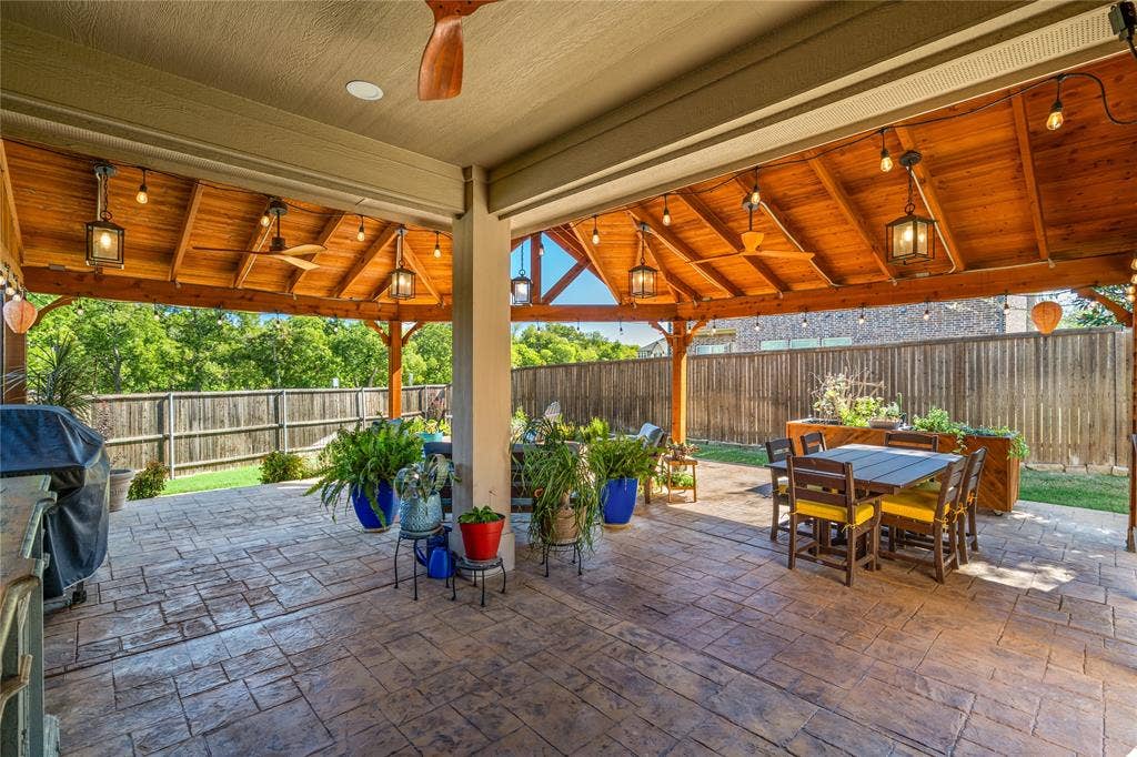 Covered patio featuring a vaulted wood-plank ceiling, stamped concrete flooring, multiple ceiling fans, and built-in lantern-style lighting