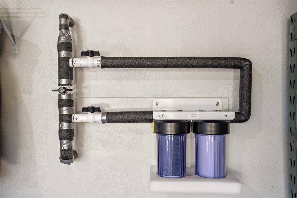 Wall-mounted dual-canister water filtration system with insulated piping and manual shut-off valves