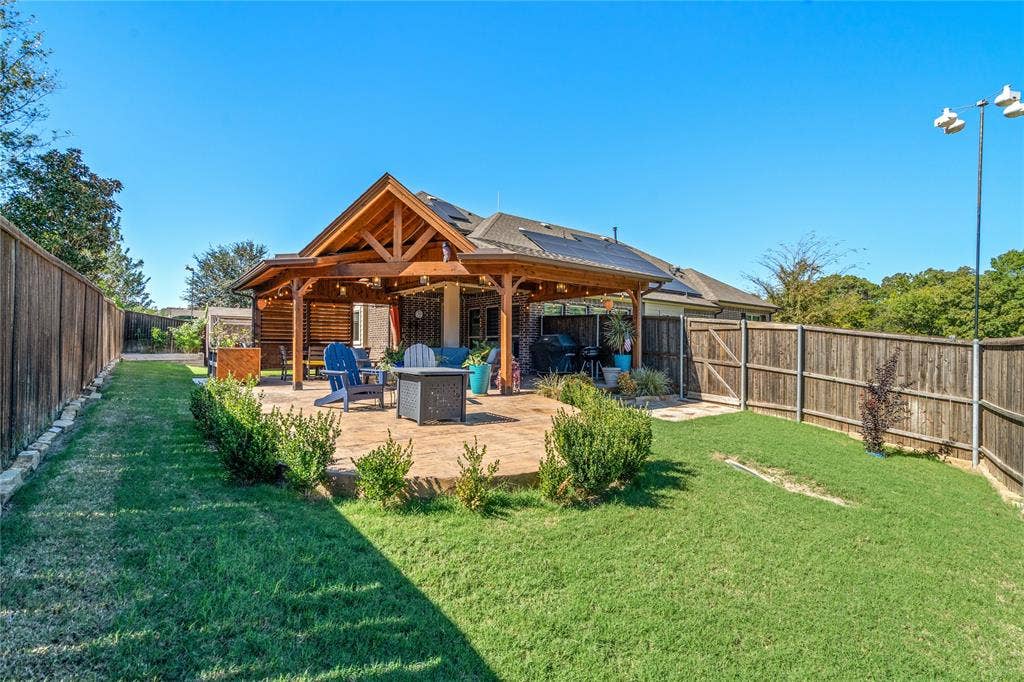Backyard featuring a timber-frame covered patio, paver stone flooring, and solar panels