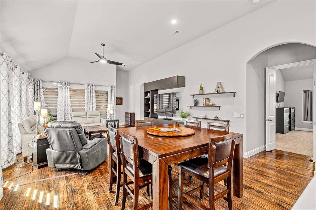 Vaulted ceilings, wood-finish flooring, built-in cabinetry, arched entryway, and wall-mounted shelving