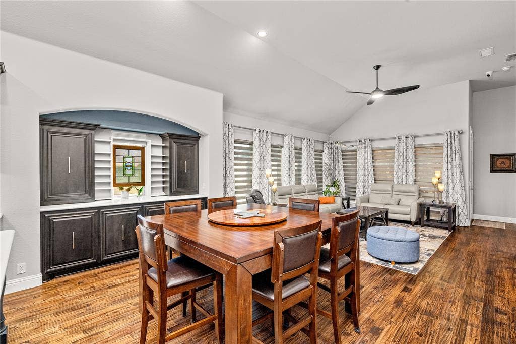 Vaulted ceiling featuring a ceiling fan, wood-finish flooring, and built-in cabinetry with a recessed arched display niche