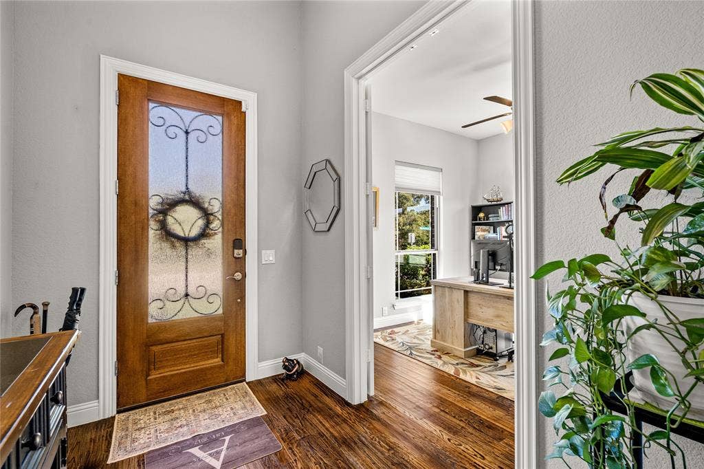 Entryway featuring a wood-finish door with decorative glass inlay, wood-finish flooring, and crown molding
