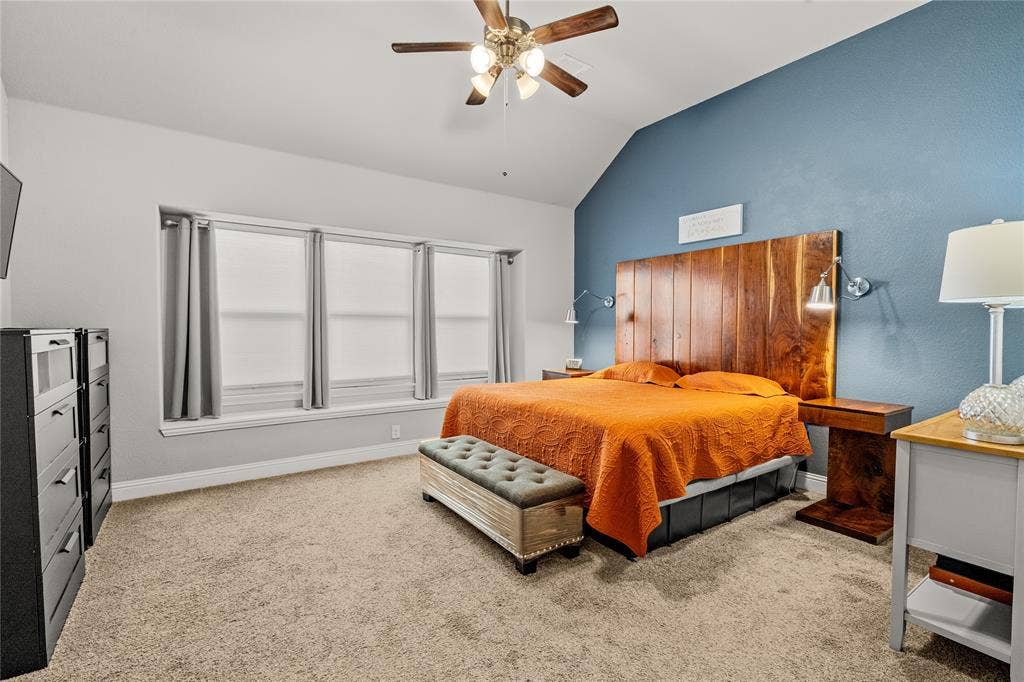Vaulted ceiling with a wood-finish ceiling fan, expansive triple-pane window configuration, and a built-in vertical wood-plank accent wall with integrated wall-mounted lighting