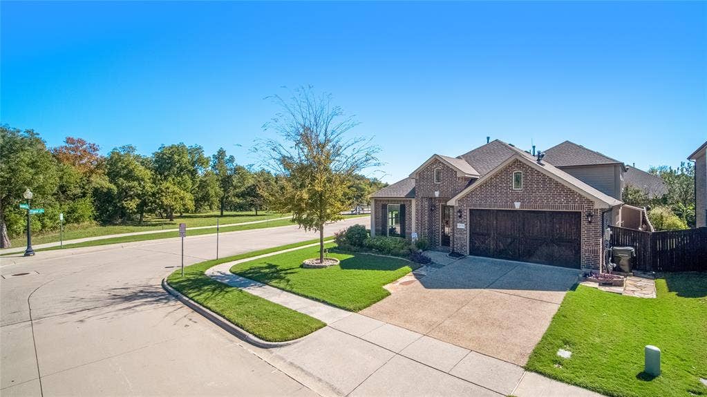 Brick exterior with multi-gabled roofline, concrete driveway, and attached two-car garage