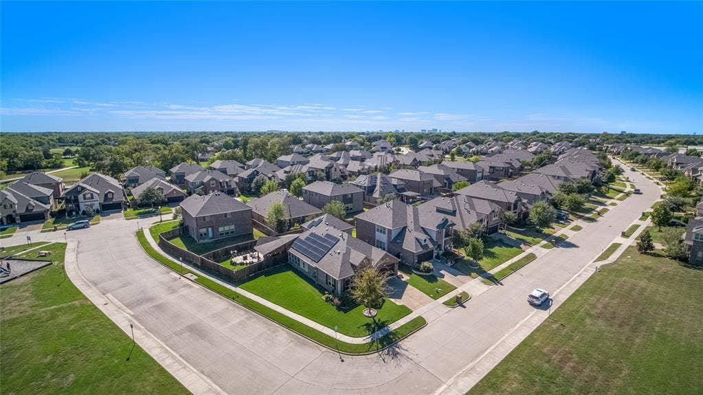 Corner lot featuring a multi-story residence with a composite shingle roof, roof-mounted solar panels, a fenced backyard, and concrete driveway