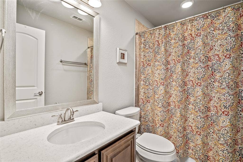 Bathroom featuring a vanity with a light-toned countertop, integrated oval basin, framed mirror, polished metal hardware, and a tub-shower combination