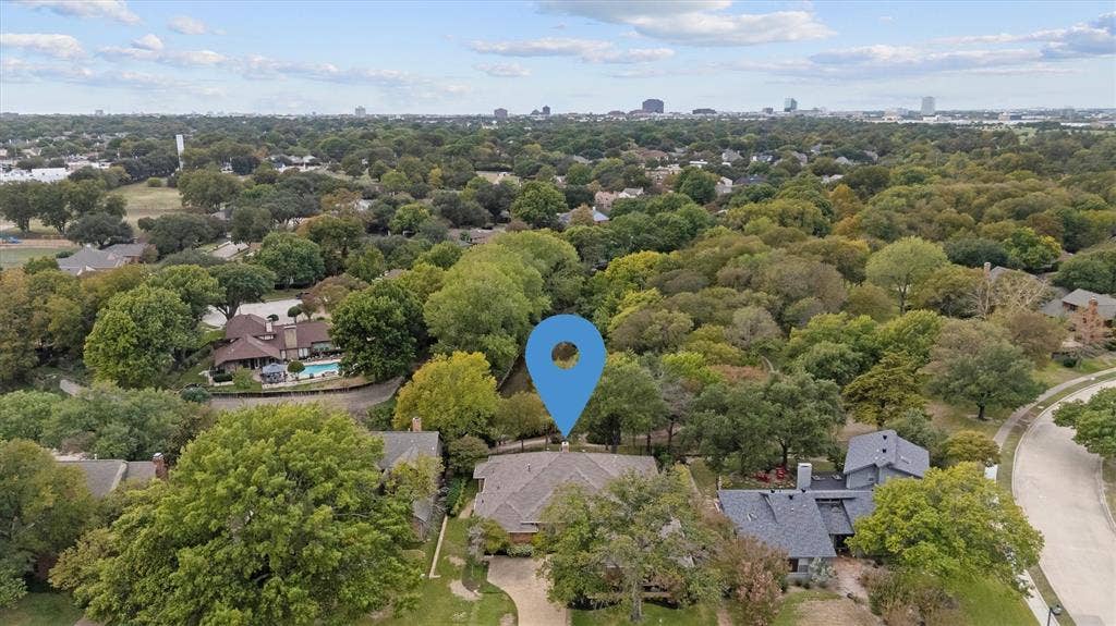 Aerial perspective featuring a residential lot with mature trees and a multi-pitched roofline