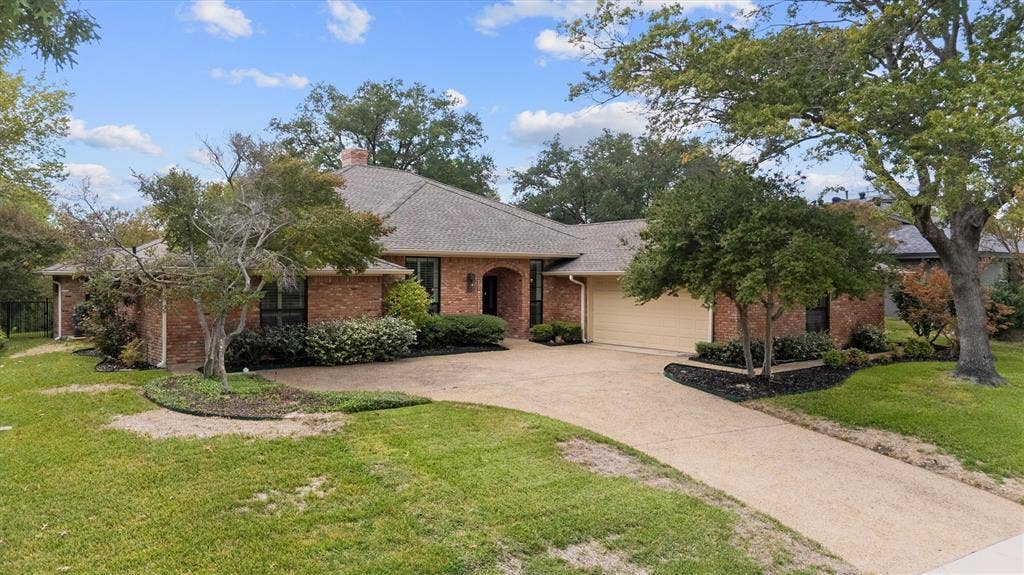 Single-story brick exterior featuring a multi-gabled roofline, an integrated two-car garage, and a concrete driveway