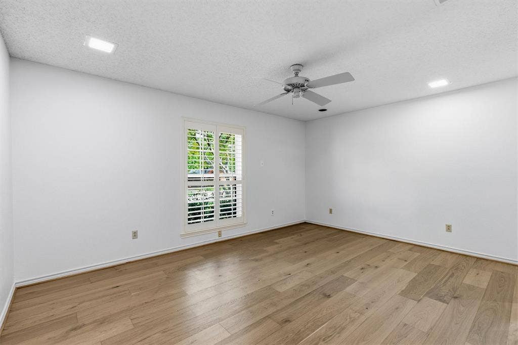 Interior space featuring wood-finish flooring, recessed lighting, a ceiling fan, and a window with plantation-style shutters