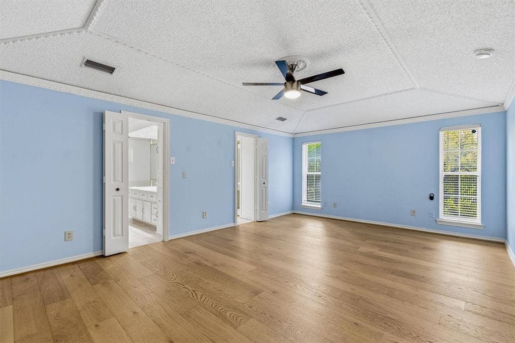 Vaulted ceiling with decorative molding, wood-finish flooring, and a central ceiling fan