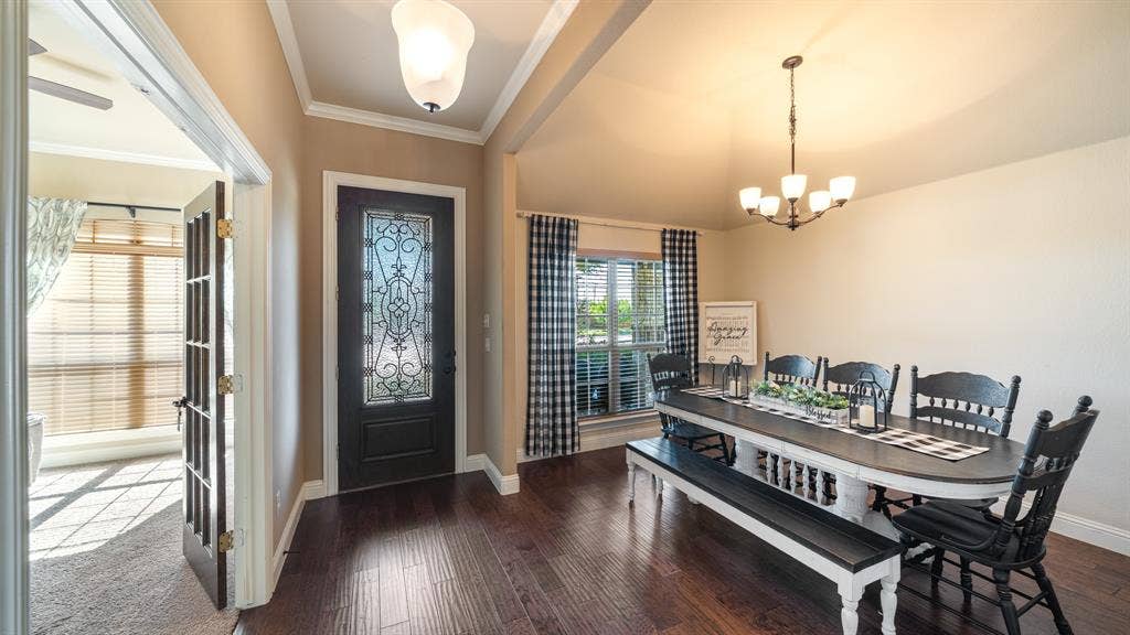 1802 Watermark Lane, Wylie, TX 75098 Entry featuring wood-finish flooring, a dark-toned door with decorative glass inlay, arched ceilings, and a multi-light chandelier