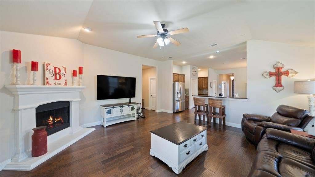 1802 Watermark Lane, Wylie, TX 75098 Living area featuring vaulted ceilings, wood-finish flooring, a neutral color palette, and a white mantle fireplace