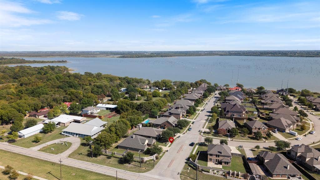 1802 Watermark Lane, Wylie, TX 75098 Aerial perspective of residential lots situated along a large body of water, featuring mature trees and paved street infrastructure