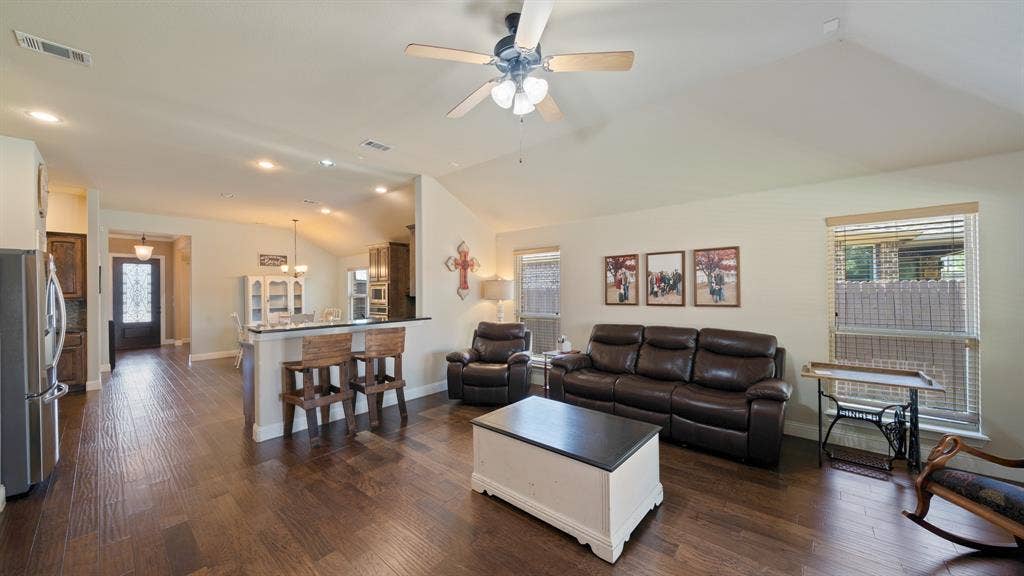 1802 Watermark Lane, Wylie, TX 75098 Open concept living area featuring vaulted ceilings, wood-finish flooring, recessed lighting, and a breakfast bar with built-in cabinetry