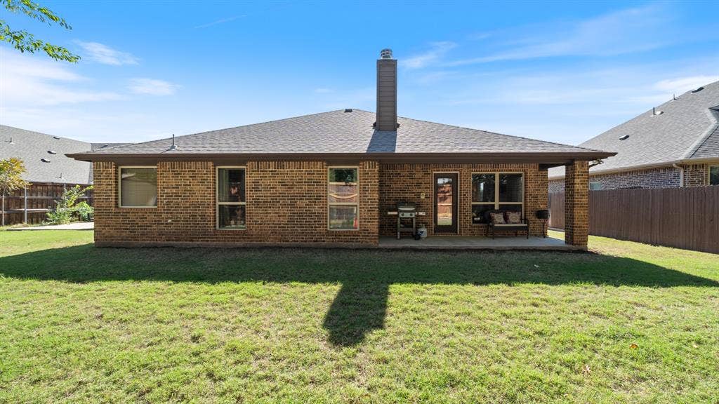 1802 Watermark Lane, Wylie, TX 75098 Rear exterior featuring brick siding, a covered concrete patio, a chimney, and a fenced backyard
