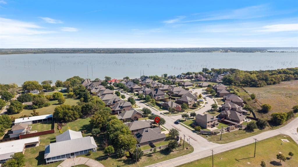 1802 Watermark Lane, Wylie, TX 75098 Aerial perspective of a residential neighborhood featuring waterfront positioning, expansive open water, mature tree coverage, and paved street access