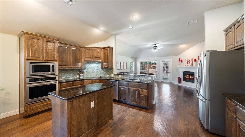 1802 Watermark Lane, Wylie, TX 75098 Kitchen featuring stained wood cabinetry, stone countertops, stainless steel wall-mounted oven and microwave, recessed lighting, and wood-finish flooring