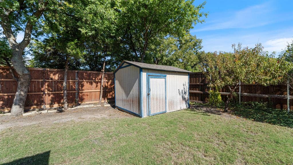 1802 Watermark Lane, Wylie, TX 75098 Backyard featuring a wood storage shed, privacy fencing, and mature trees
