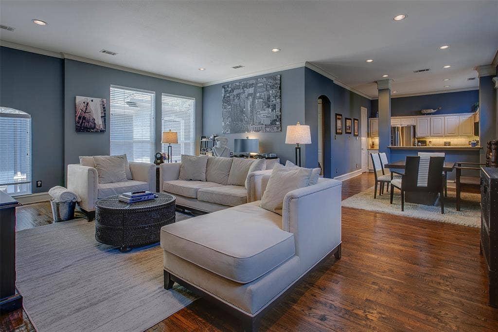 Open-concept living area featuring rich wood-finish flooring, recessed lighting, and a neutral wall palette