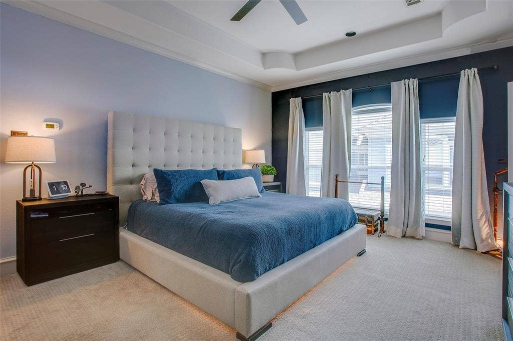 Carpeted bedroom featuring a tray ceiling, recessed lighting, and a neutral upholstered tufted headboard