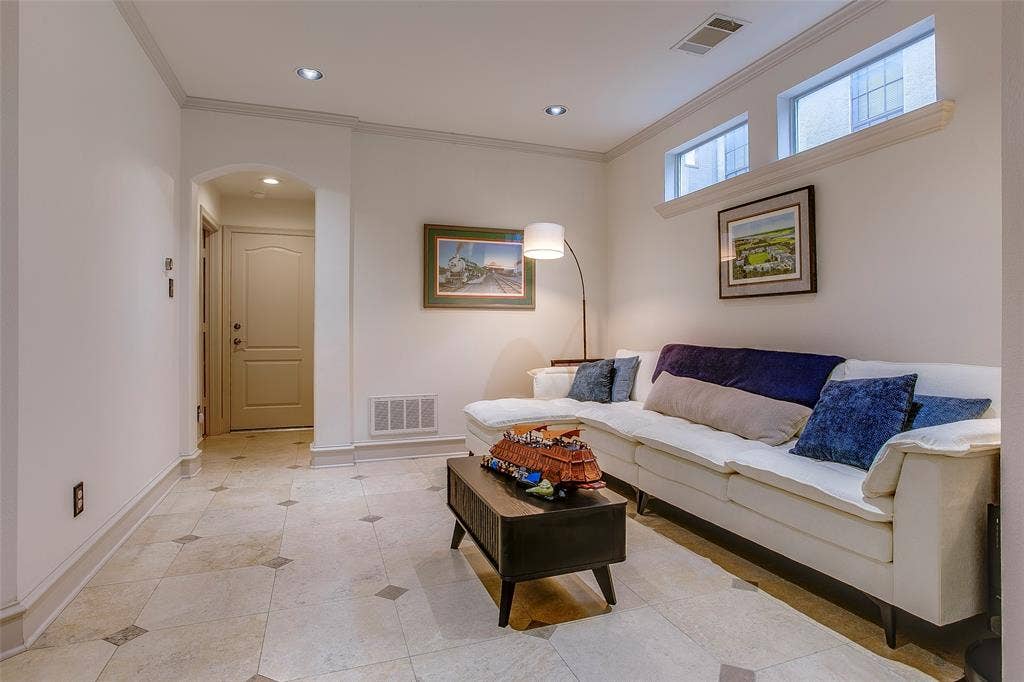 Living area featuring tile flooring with decorative inserts, recessed lighting, and crown molding