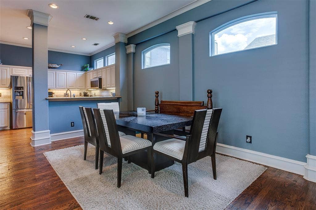 Dining area featuring wood-finish flooring, architectural columns, and arched transom windows