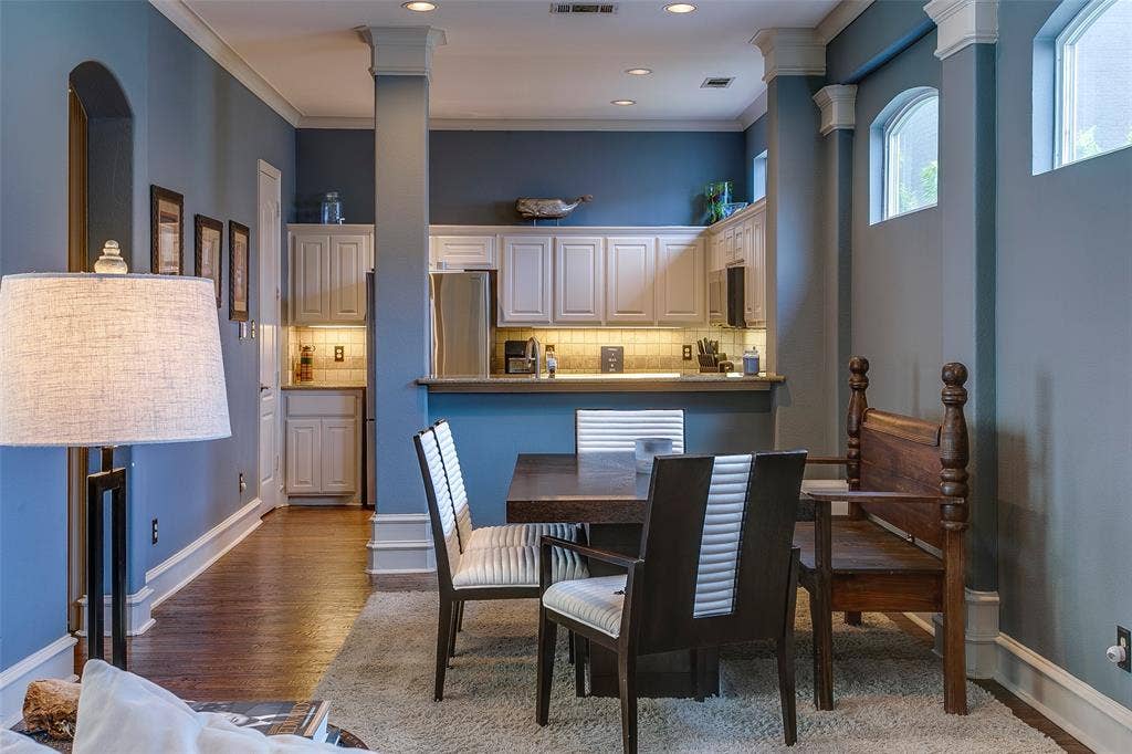 Open-concept living area featuring wood-finish flooring, a kitchen with light-toned cabinetry and stainless steel appliances, and a dining space with a dark wood table