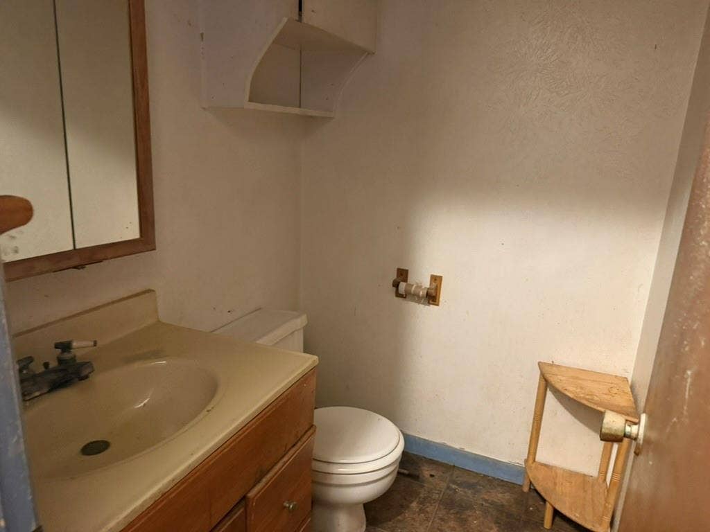 Vanity featuring an integrated sink, wooden cabinetry, wall-mounted medicine cabinet, overhead built-in shelving, and tile flooring