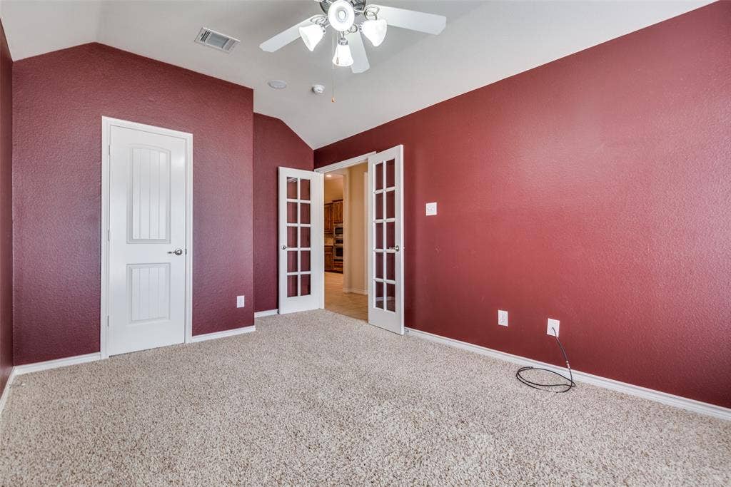 Spare room with french doors, visible vents, a ceiling fan, and lofted ceiling