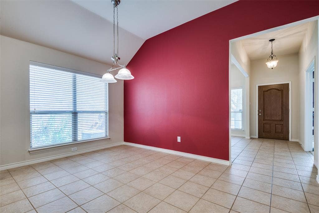 Unfurnished room featuring light tile patterned floors, baseboards, an inviting chandelier, and vaulted ceiling