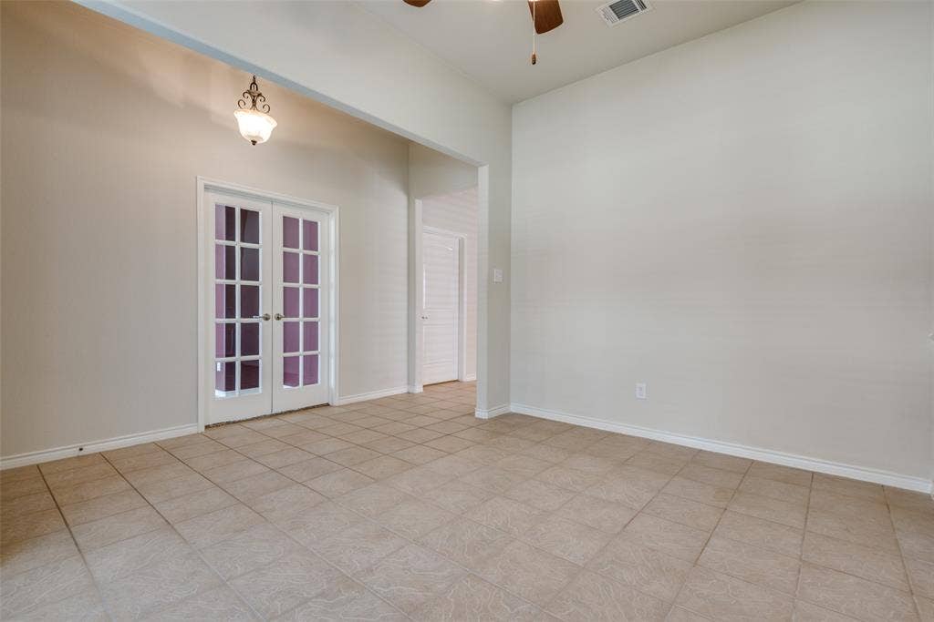 Empty room featuring french doors, baseboards, visible vents, and ceiling fan