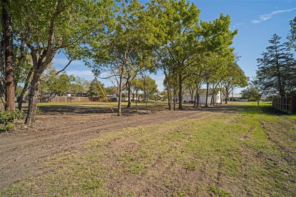 415 S Bell Street, Royse City, TX 75189 Expansive level lot featuring mature trees, partial fencing, and open green space