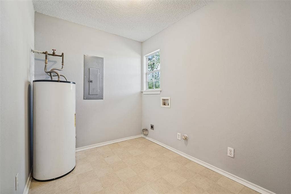 415 S Bell Street, Royse City, TX 75189 Utility room featuring an electric water heater, integrated electrical panel, wall-mounted window, and dedicated washer and dryer hookups