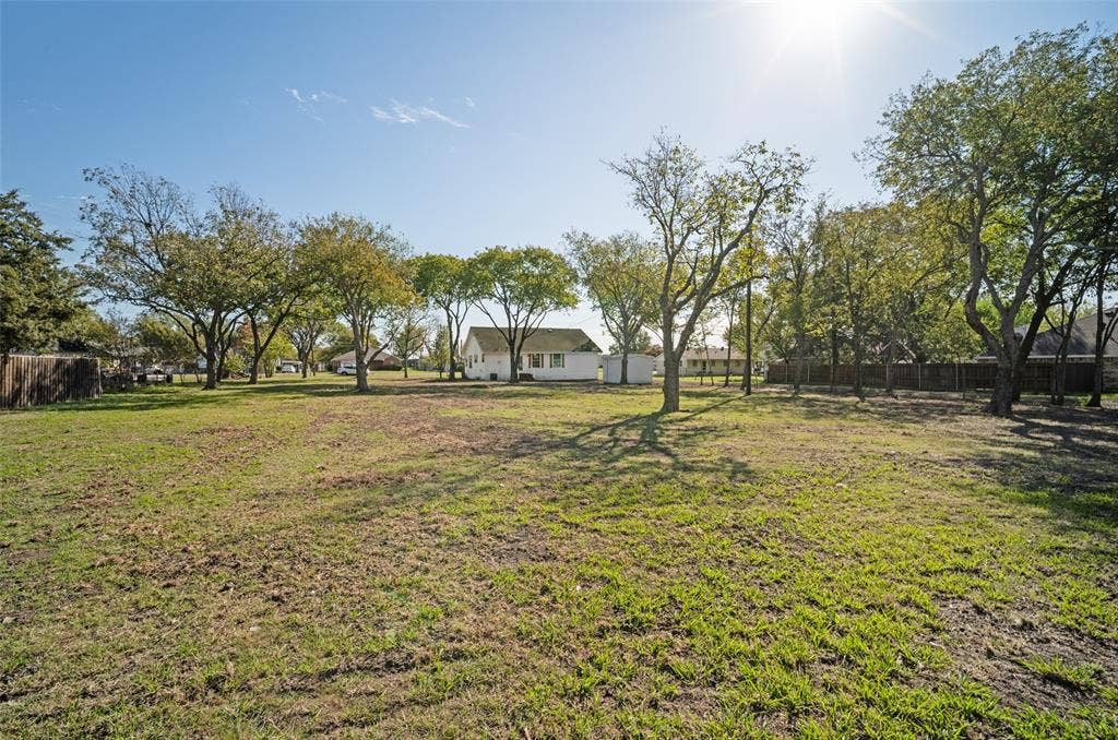 415 S Bell Street, Royse City, TX 75189 Expansive backyard featuring mature trees, wood privacy fencing, and a detached storage structure