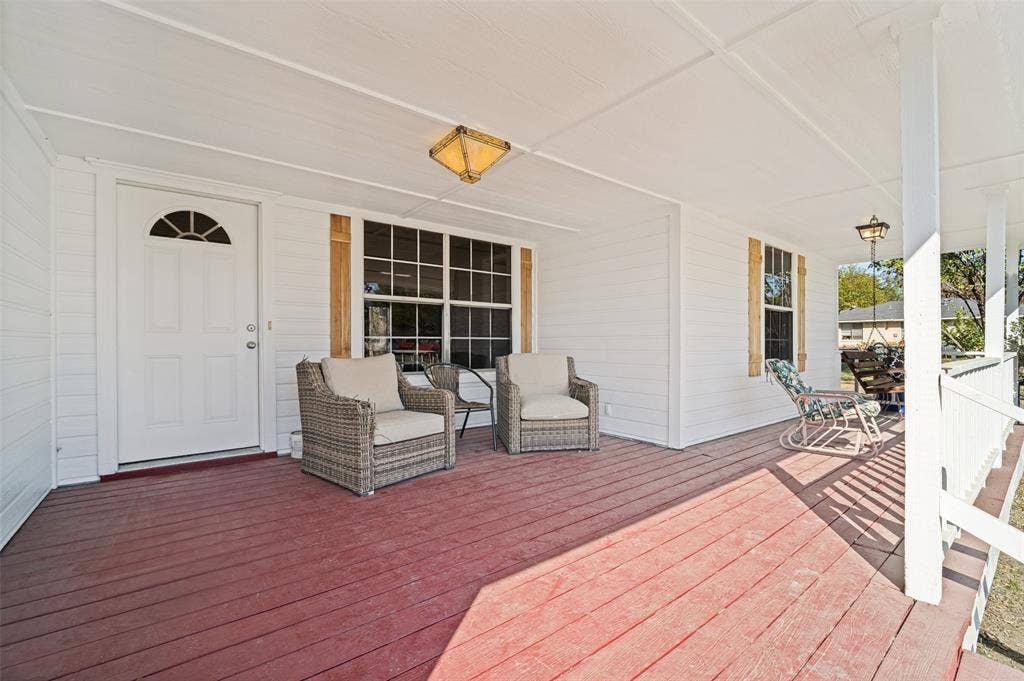415 S Bell Street, Royse City, TX 75189 Covered front porch featuring wood-plank decking, white horizontal siding, decorative wood shutters, and dual flush-mount ceiling fixtures